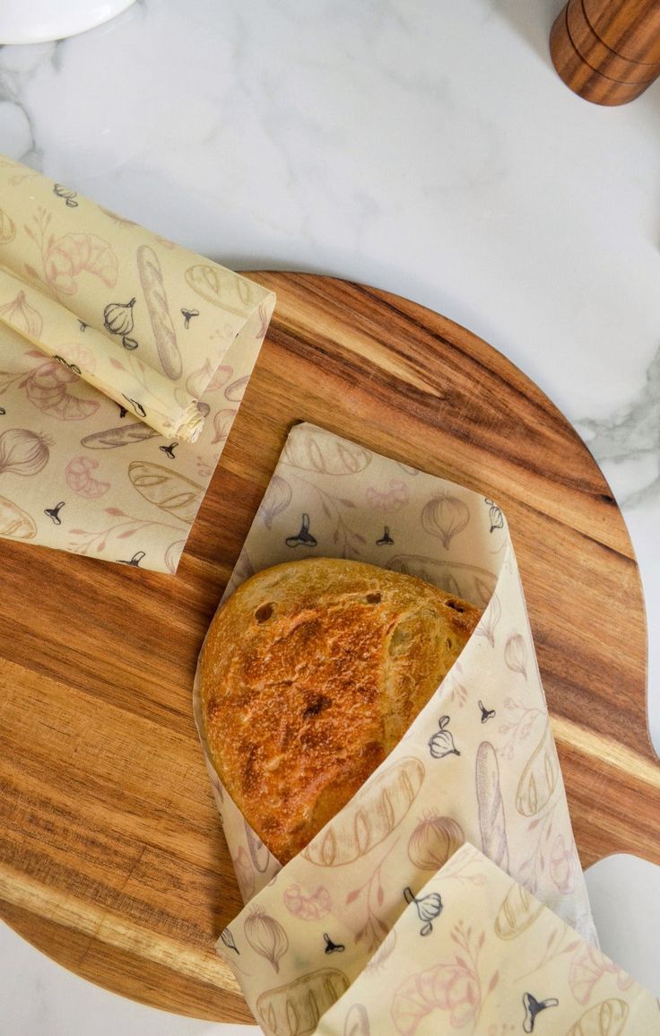 a piece of bread sitting on top of a wooden cutting board next to napkins