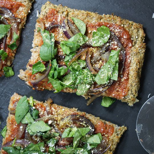 four slices of pizza with various toppings and wine glass on the table next to it