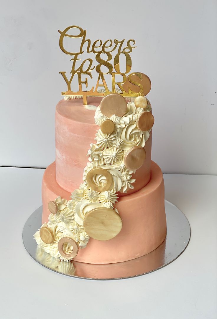 a pink and gold cake with flowers on top