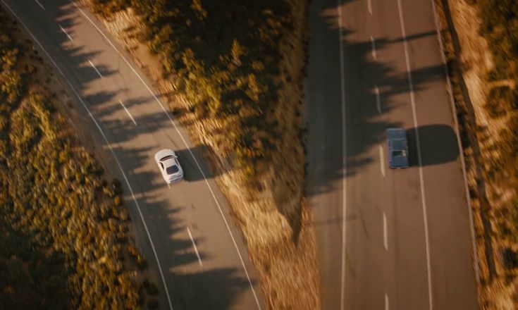 an aerial view of two cars driving down a road