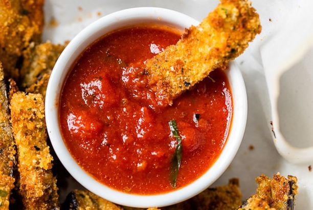 some fried food is in a white bowl and sauce on the plate next to it