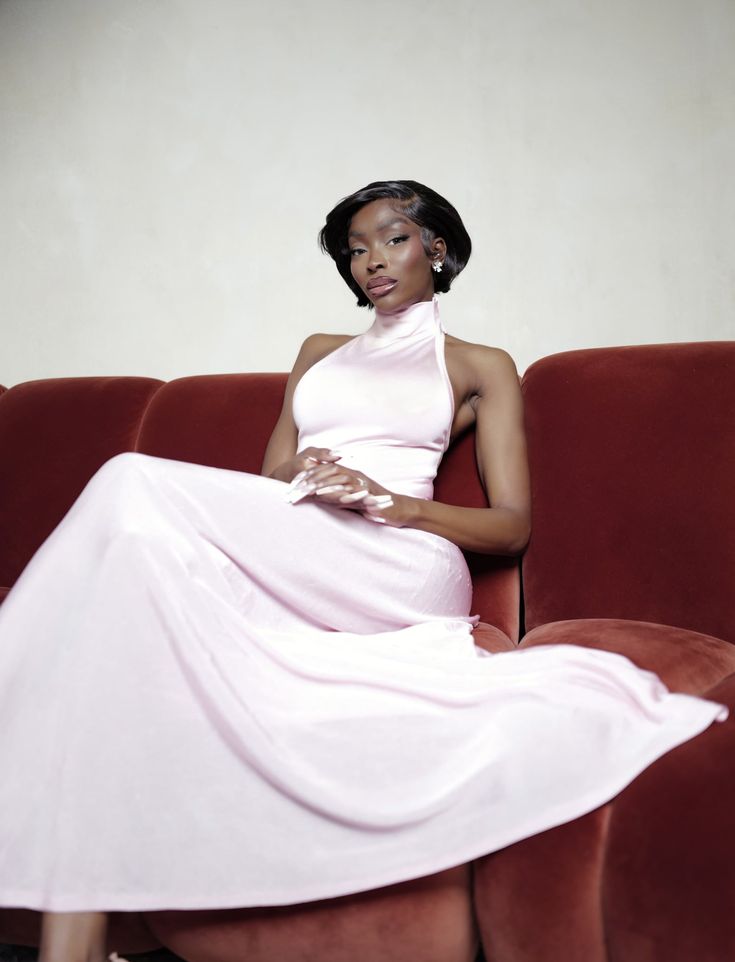 a woman in a pink dress sitting on a red couch