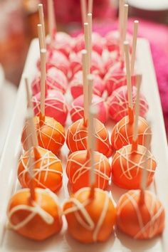 there are many orange candies on the white platter with toothpicks in them