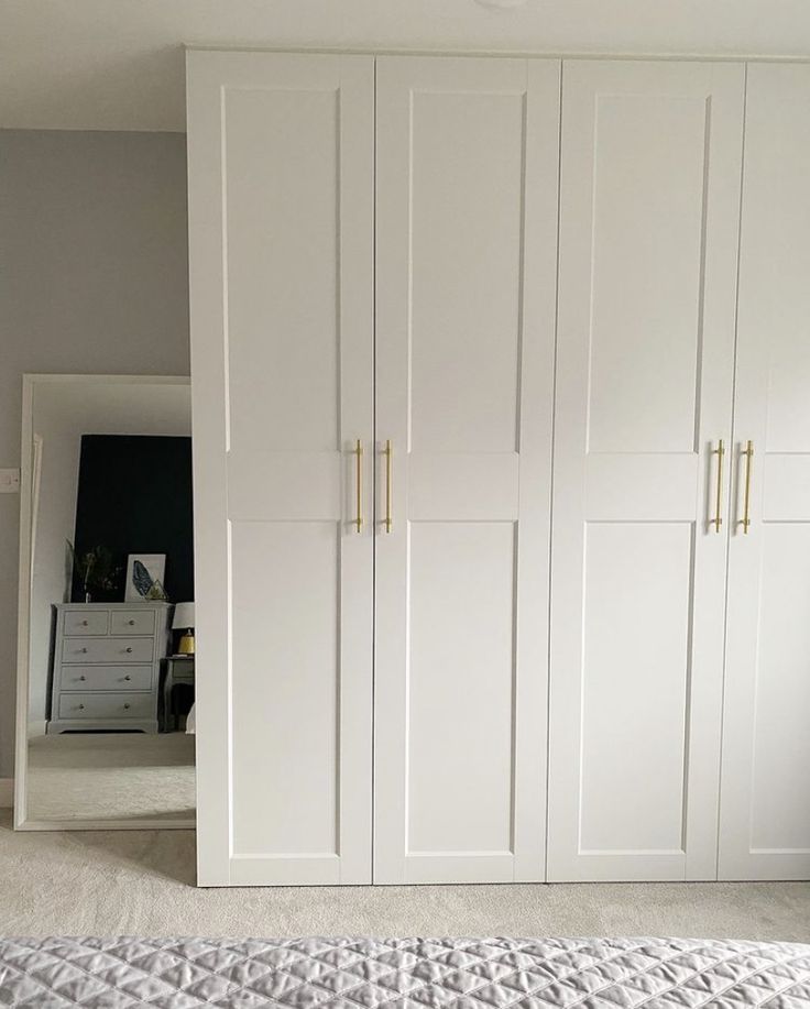 a bedroom with white closets and carpeted flooring in front of the bed