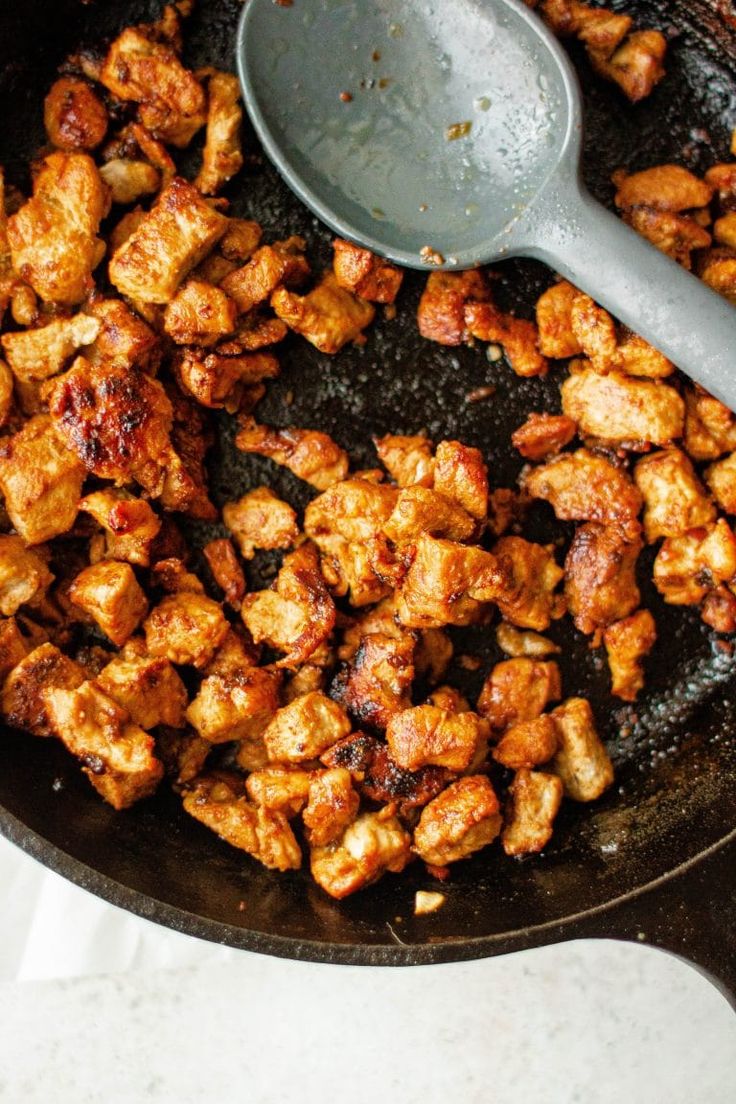 chicken is being cooked in a skillet with a spatula