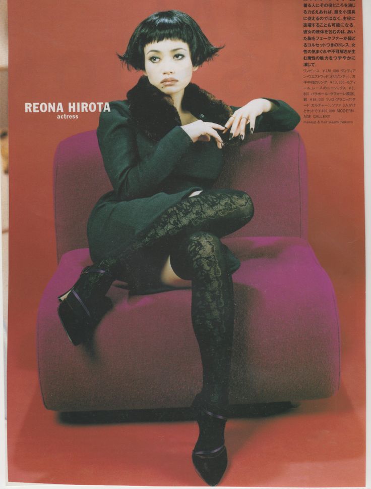 a woman sitting on top of a purple couch next to a red wall and wearing black tights