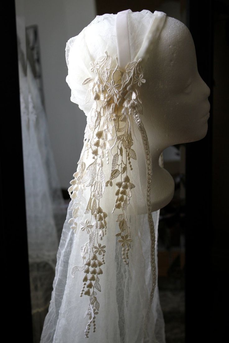 a mannequin head with white lace and flowers on it's neckline