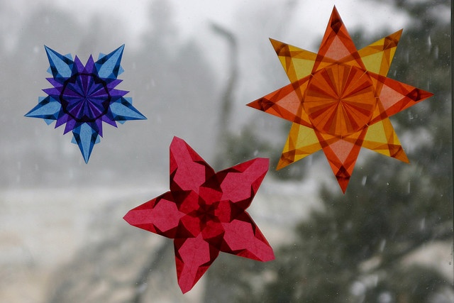 three colorful paper stars hanging from a window