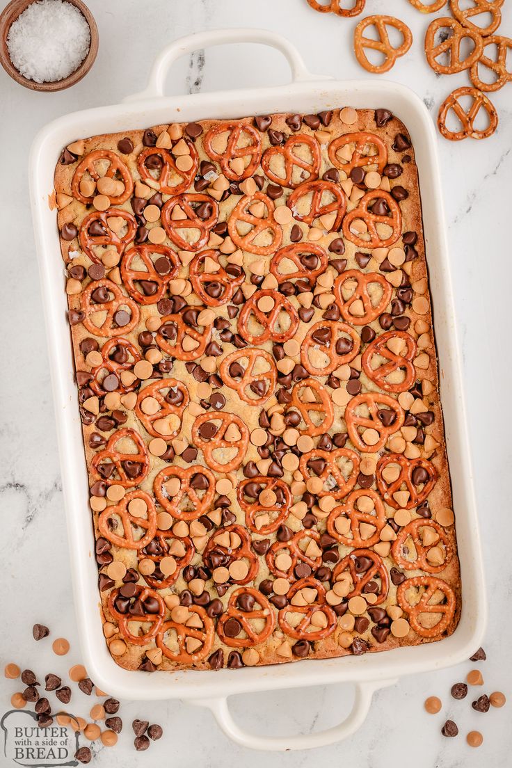 a casserole dish with pretzels and chocolate chips in it on a marble surface