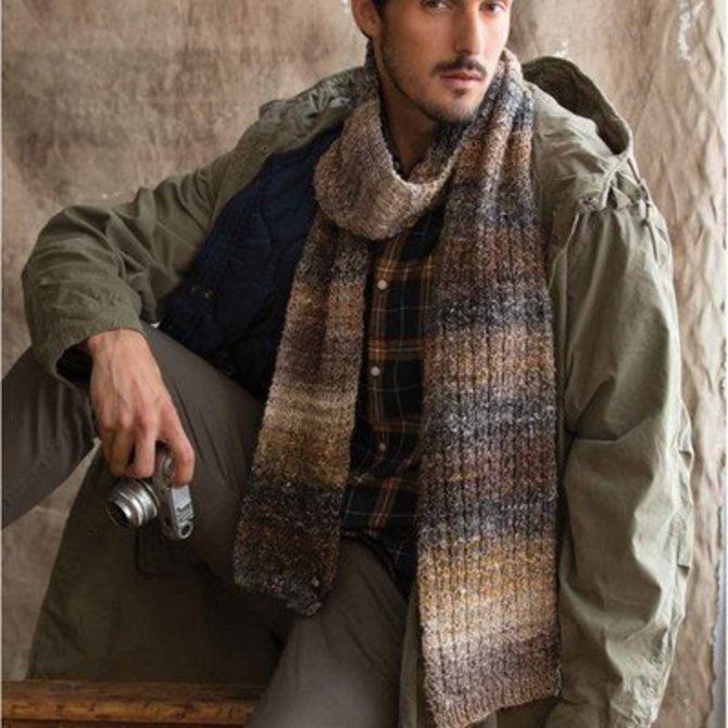 a man wearing a hat and scarf sitting on a bench with a camera in his hand