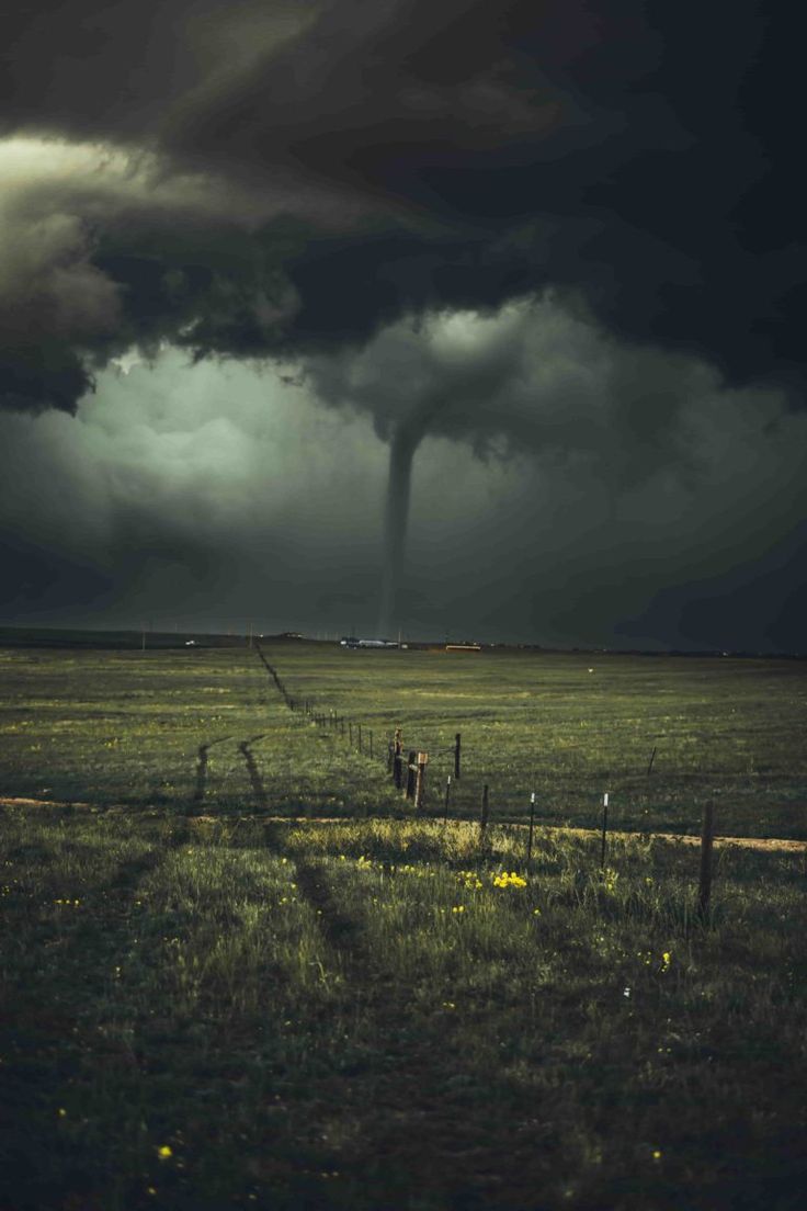 a large tornado is in the sky over a grassy field