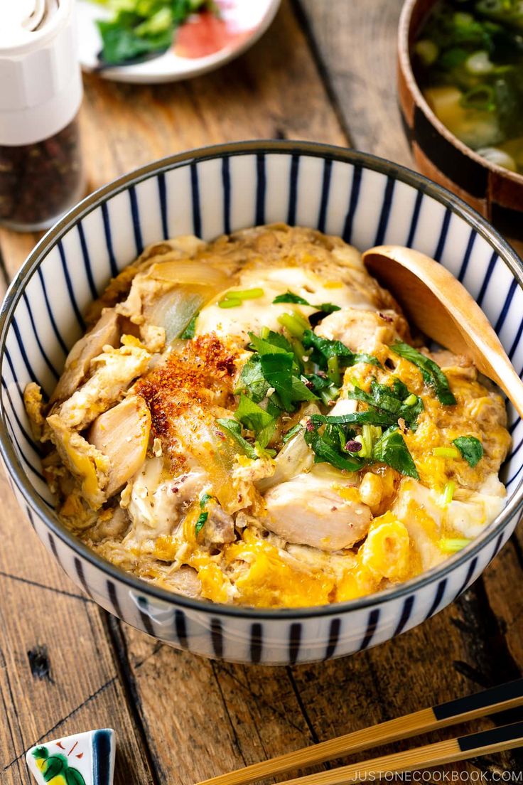 a bowl filled with food sitting on top of a table next to chopsticks