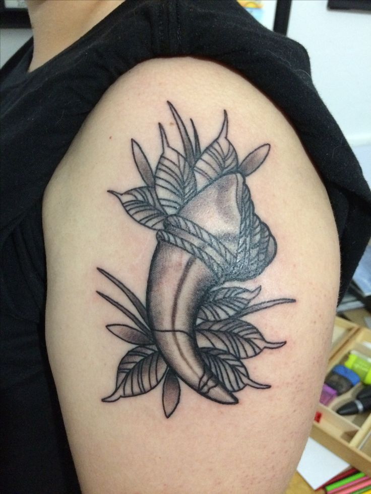 a woman's arm with a black and white tattoo design on the left shoulder