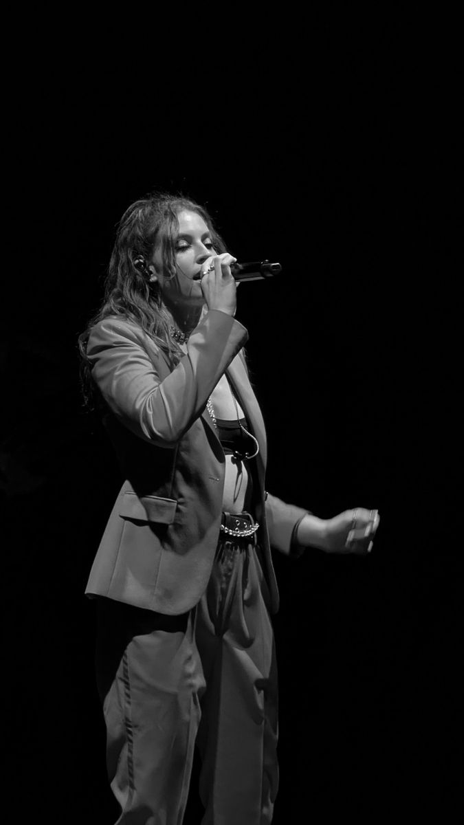 a woman in a suit singing into a microphone