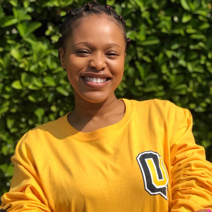 a woman in a yellow shirt is smiling at the camera with her arms folded out