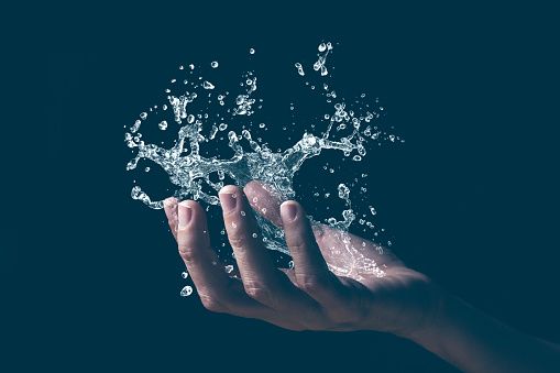 a person's hand holding water in the air