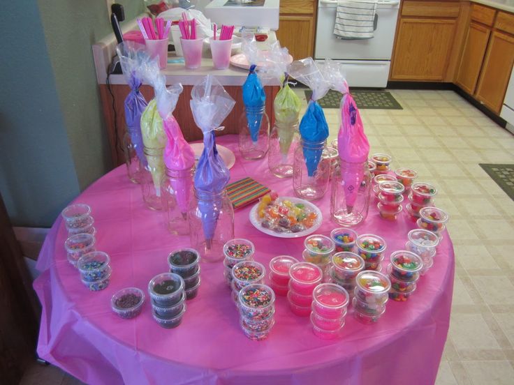 a pink table topped with lots of cupcakes and candy