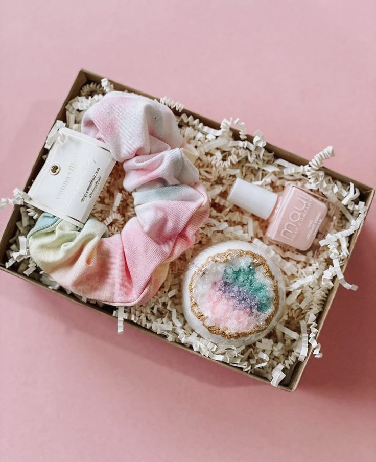 an open box with some items inside on a pink surface, including soaps and other things