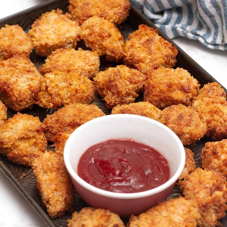 fried food on a tray with ketchup in a small bowl next to it