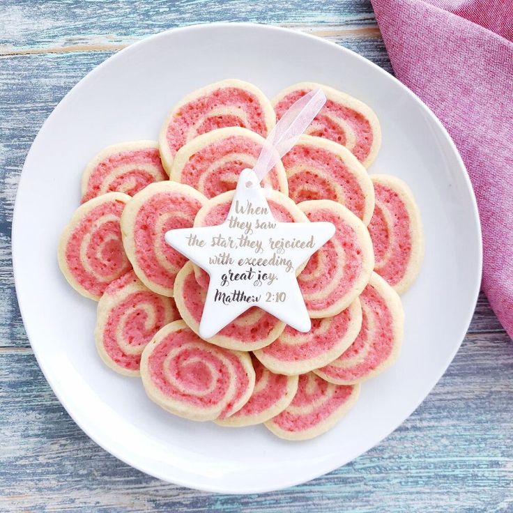 a white plate topped with cookies covered in pink frosting and a star ornament