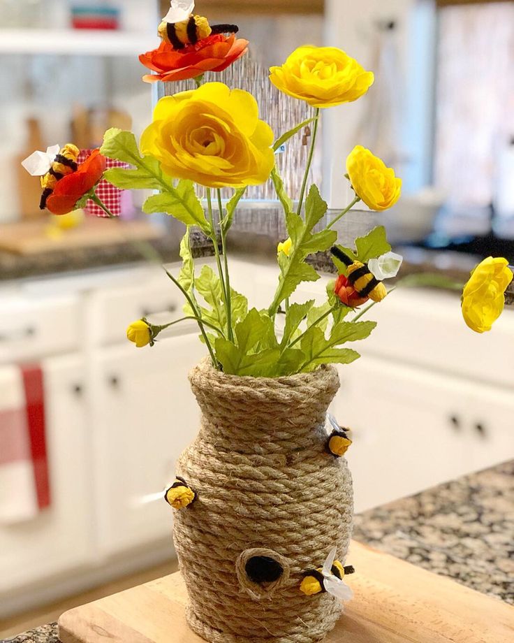 a vase filled with yellow flowers on top of a wooden table next to a kitchen counter