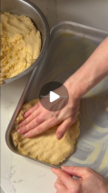 two hands are kneading dough in a pan on a counter top, and another hand is reaching for it