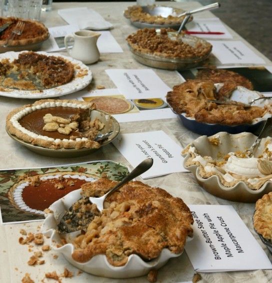 a table topped with lots of pies covered in toppings