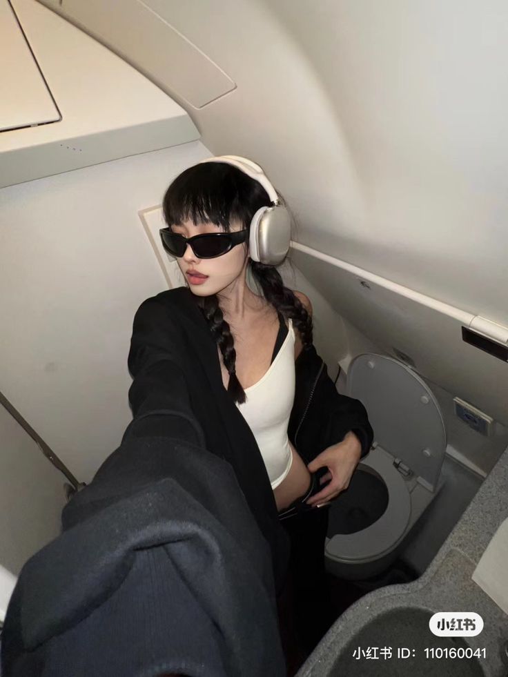 a woman wearing headphones sitting on an airplane