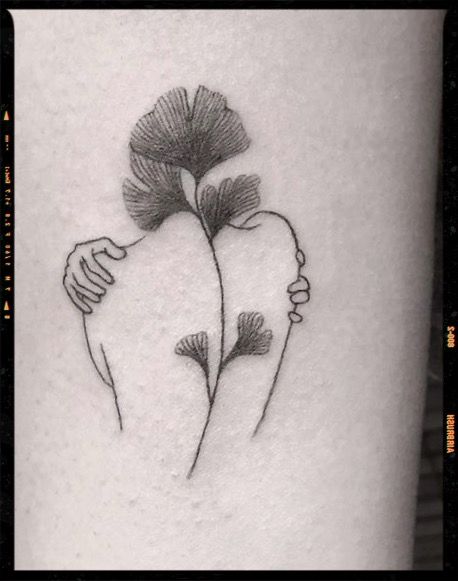 a black and white photo of two flowers on the side of a woman's leg