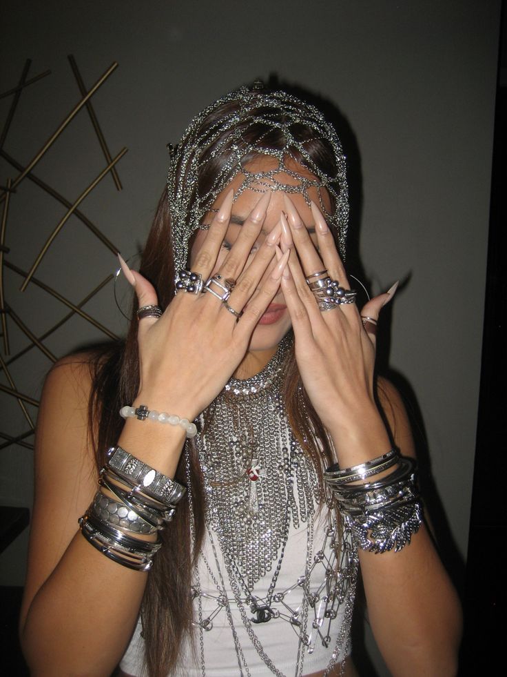 a woman covering her face with hands and wearing silver bracelets on top of her head