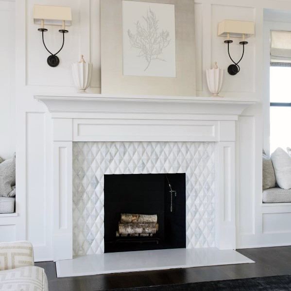 a white fireplace in a living room next to two couches and a painting on the wall