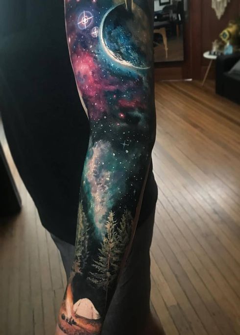 a man's arm with an image of trees and stars on it