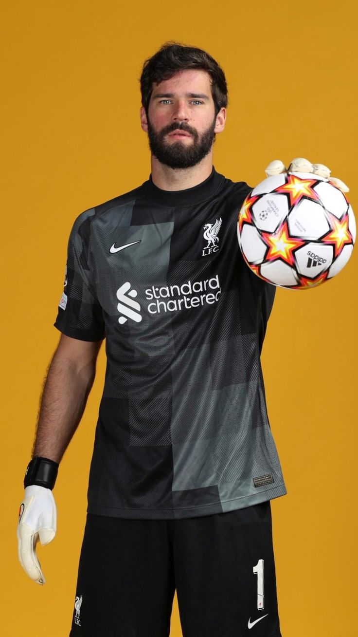 a man holding a soccer ball in one hand and wearing gloves on the other side