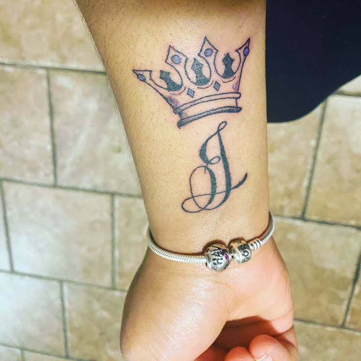 a woman's wrist with a crown tattoo on her left arm and the letter b