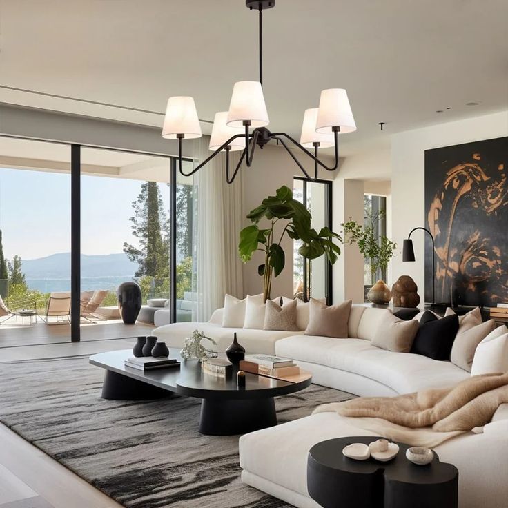 a living room filled with lots of white furniture and large windows overlooking the mountains in the distance