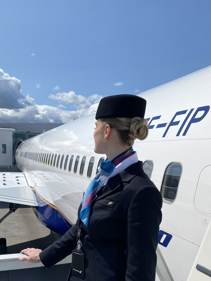 a woman in uniform standing next to an airplane on the tarmac at an airport