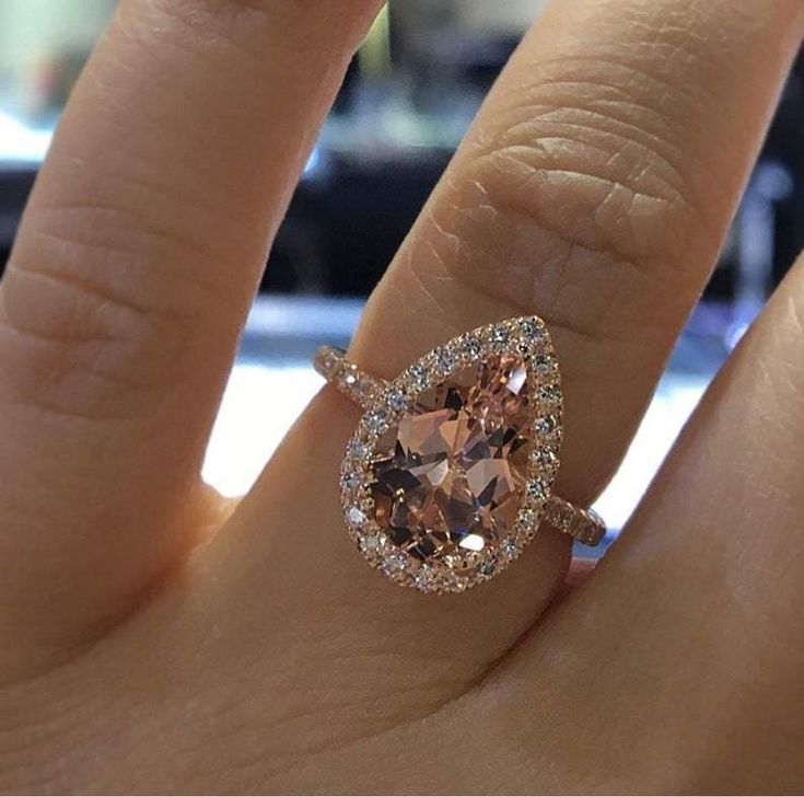 a woman's engagement ring with an oval shaped morganite and diamond halos