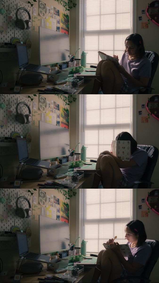 a woman sitting at a desk in front of a computer monitor and holding a book