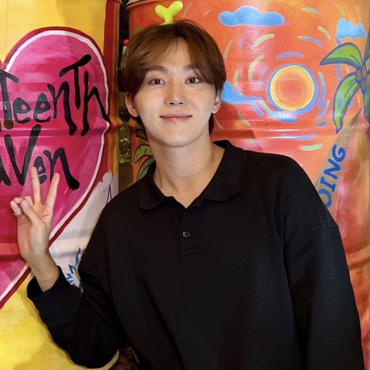 a young man standing in front of a wall with graffiti on it's side