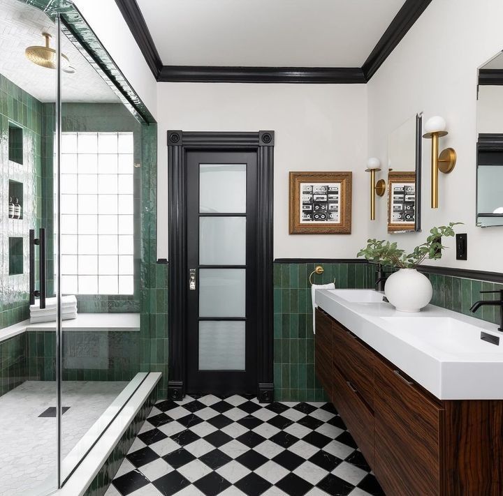 a bathroom with black and white checkered flooring, green tile walls and two sinks