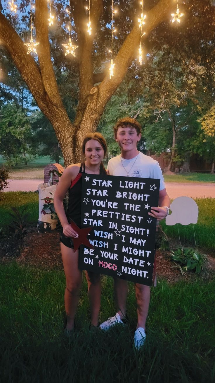 two people standing in front of a tree holding signs