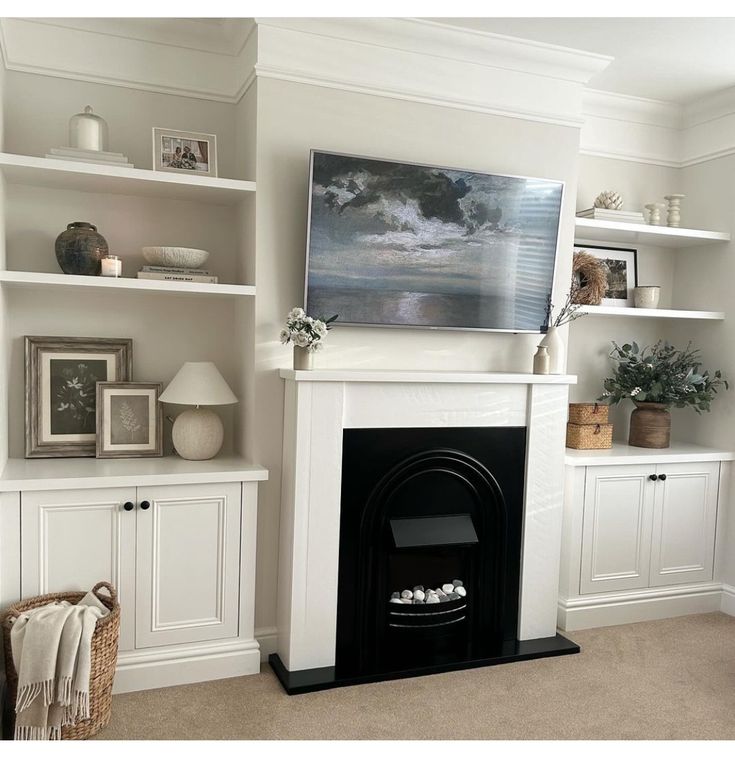 a living room with white bookcases and a fireplace