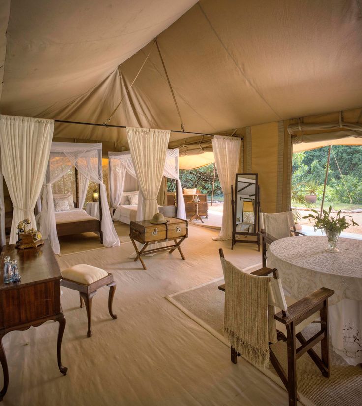 a bedroom with white drapes on the ceiling and curtains hanging from the ceiling, in front of a large window