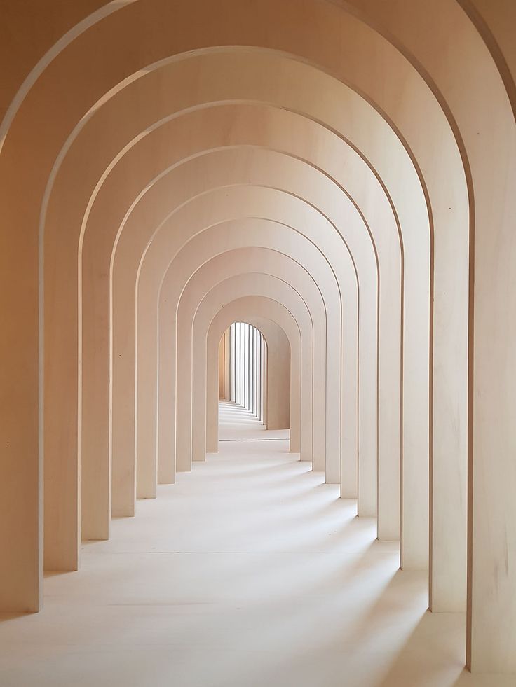 an arched hallway with white walls and columns