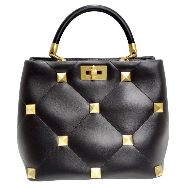 The Valentino Garavani Roman Stud Nappa Bag is a luxurious and versatile accessory that seamlessly blends sophistication with edgy detailing. Crafted from quilted black leather, the bag features an eye-catching rhombus pattern enhanced by tone-on-tone stitching, creating a timeless and chic design. The embellished gold-tone maxi studs, along with antique-brass-finish metal hardware, add a touch of opulence and an edgy vibe to the bag. Equipped with both a leather top handle and a detachable leat Valentino Rockstud Bag, Spike Bag, Rhombus Pattern, Gucci Boots, Valentino Handbags, Studded Bag, Valentino Black, Leather Baby, Small Handbags