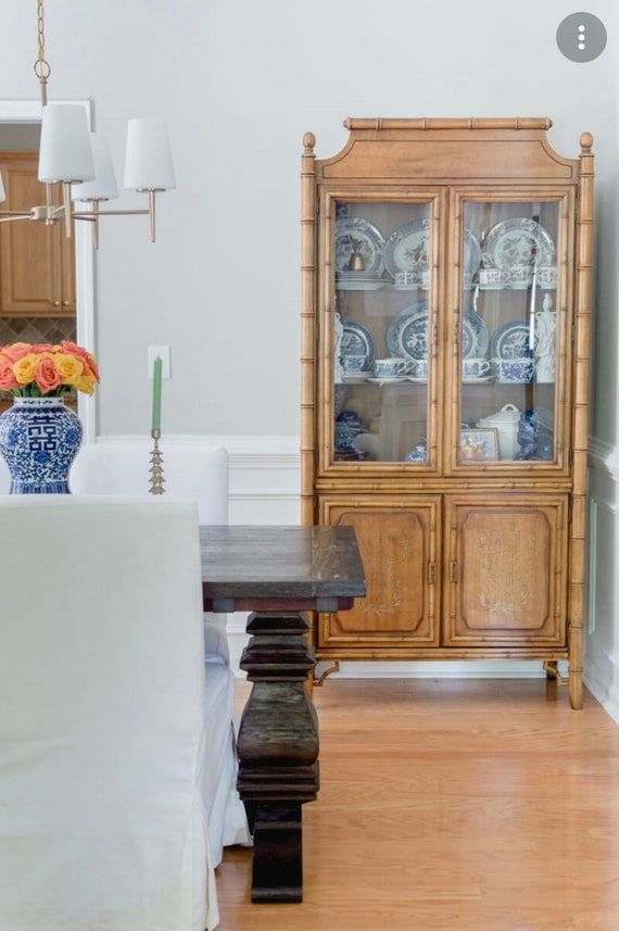 a dining room table and chairs in front of a china cabinet with plates on it