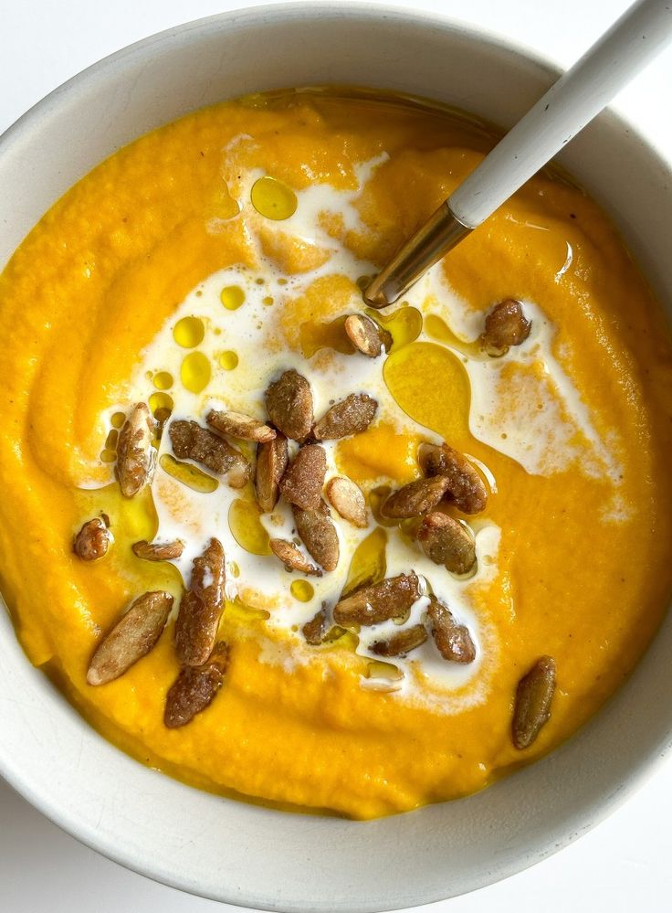 a white bowl filled with carrot soup and nuts