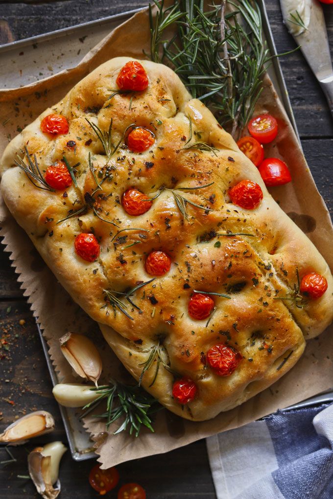 a loaf of bread with tomatoes and herbs on it