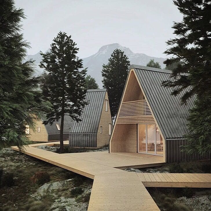 two small wooden houses in the woods with mountains in the backgroung and trees