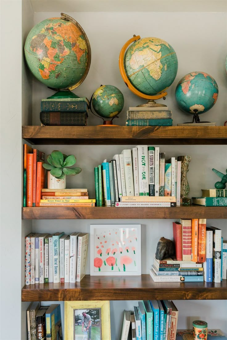 the bookshelves are filled with different types of books and globes on them